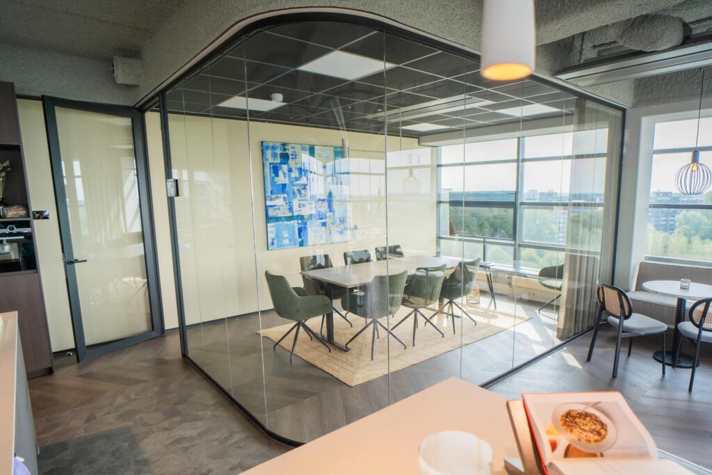 Modern glass-walled meeting room with green chairs and a blue abstract artwork at Joop Geesinkweg.